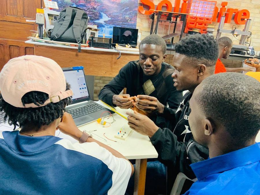 Young innovators prototyping with laptops and electronics